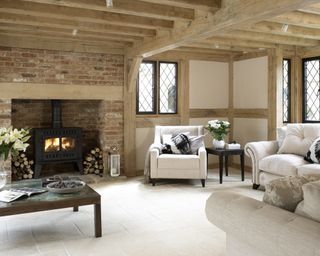A woodburning stove in an oak timbered cozy living room idea with neutral decor.