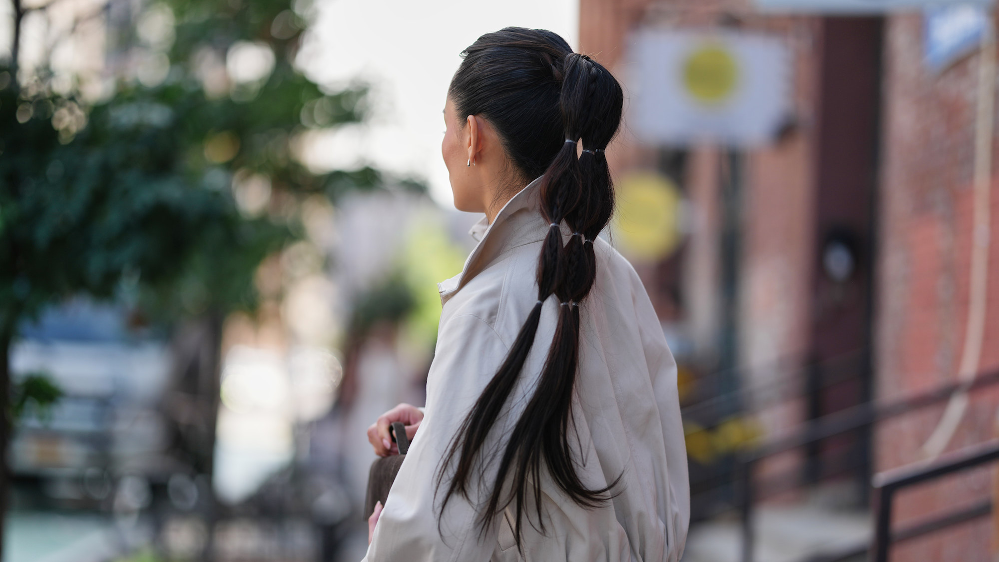 Woman wears trench coat with high bubble ponytail - best k-beauty hair products