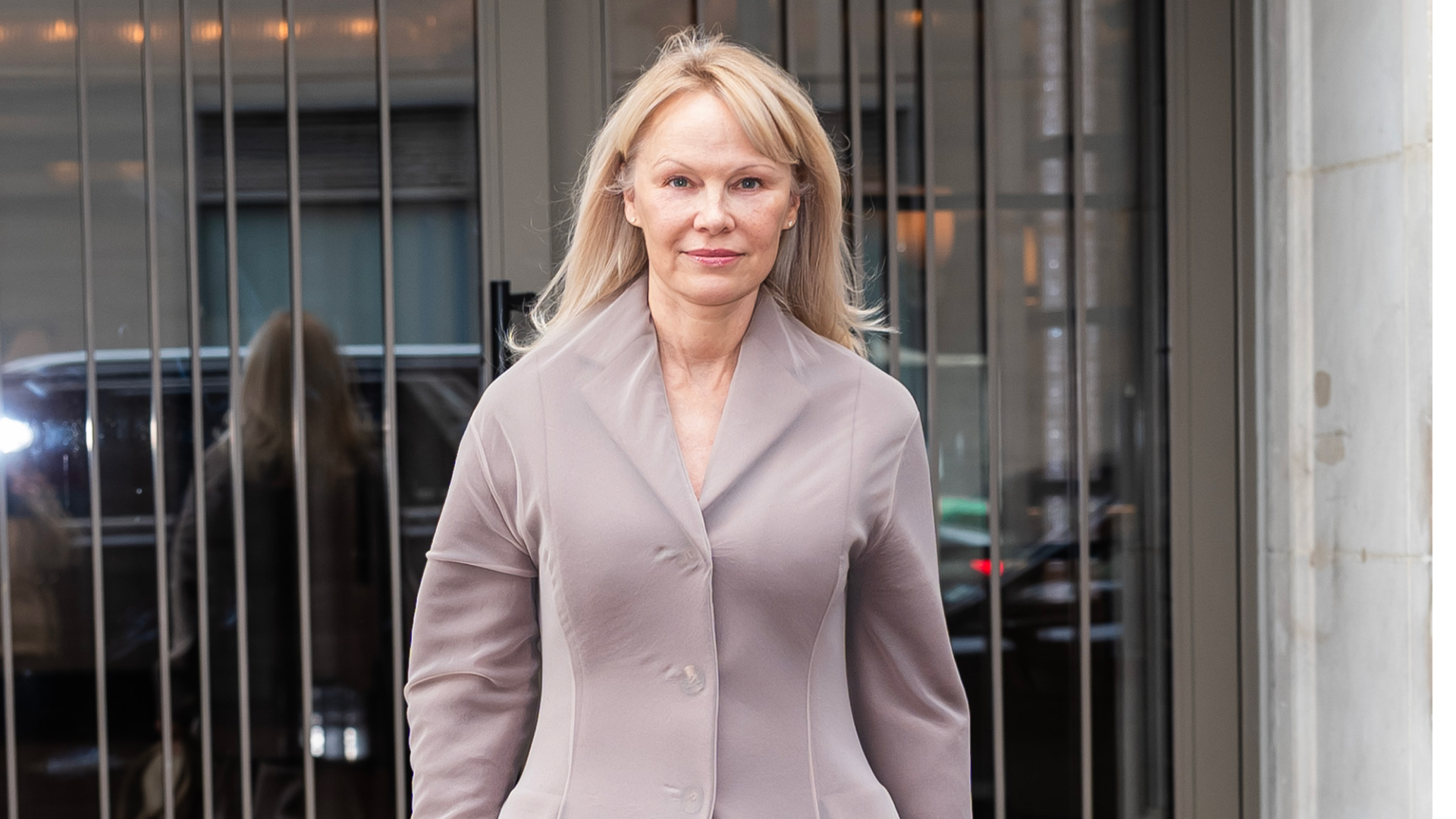 Pamela Anderson wearing a dusty mauve jacket with her hair down and no makeup.