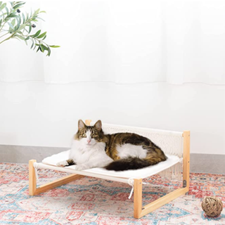 A cat sitting on top of a macrame hammock 