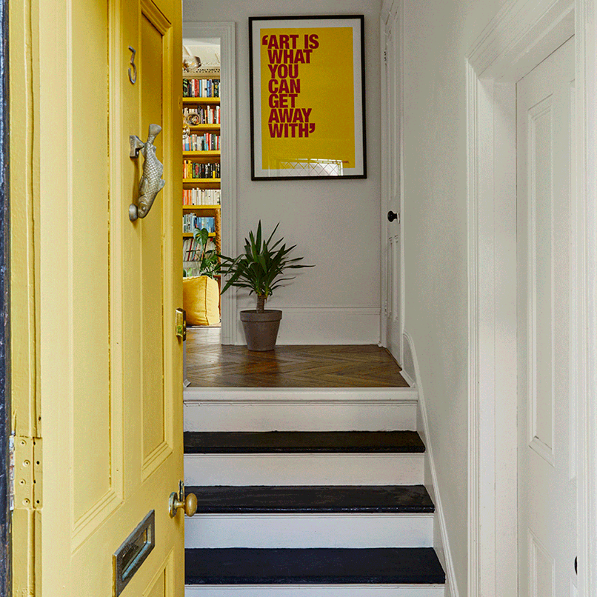 Yellow front door with steps and art work at the top
