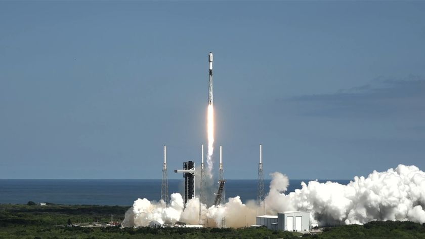 A white and black rocket lifts off against a blue sky.