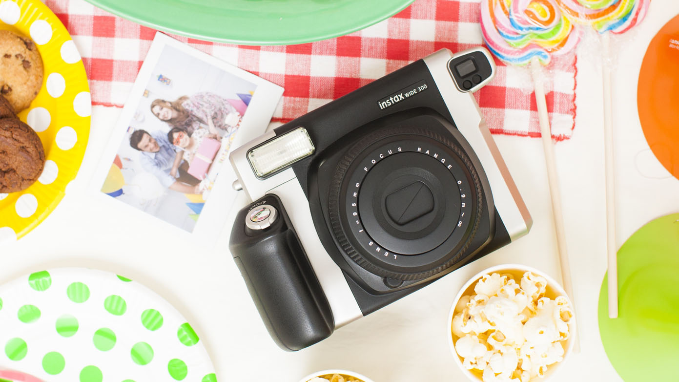 A Fujifilm Instax Wide 300 instant camera on a kitchen table during a party