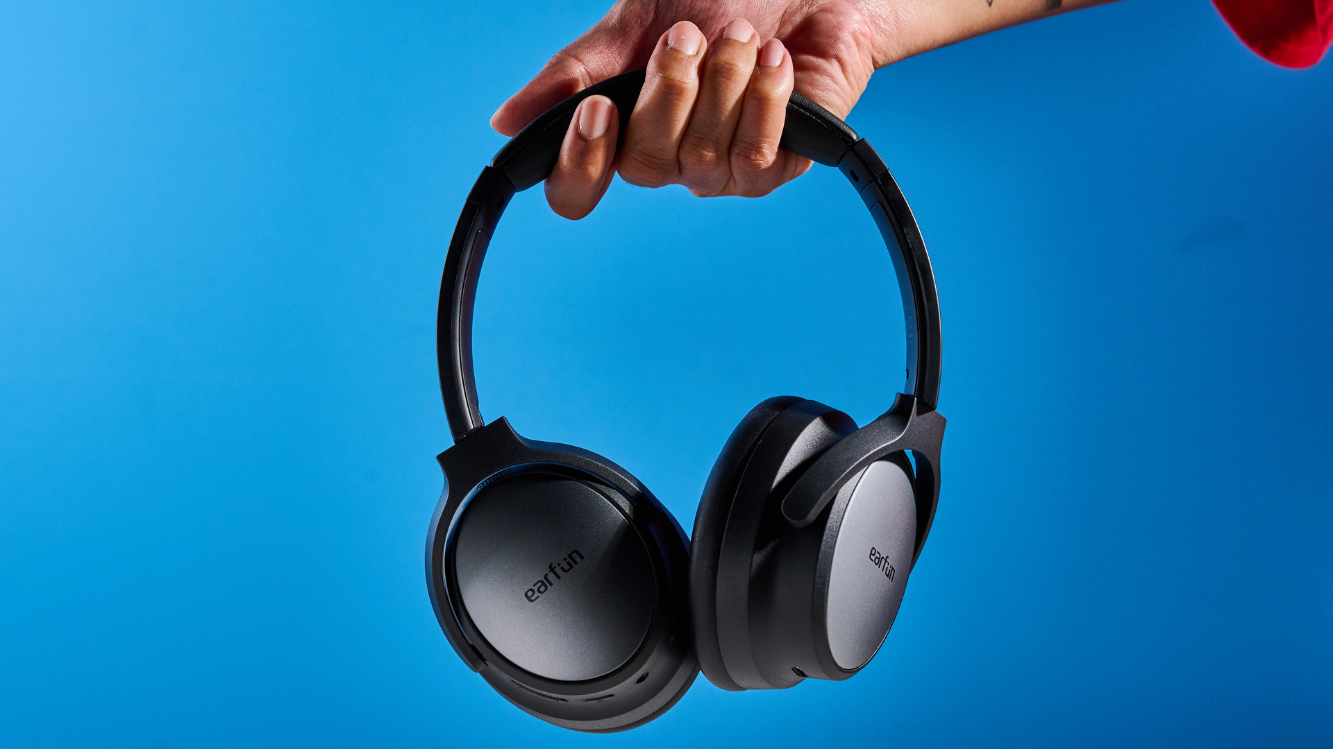 the earfun tune pro headphones, in black, with soft pleather cups, and gray cups, photographed against a blue background