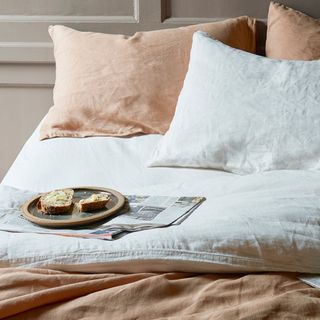 Neutral colored bedding with a newspaper and a plate with slices of bread