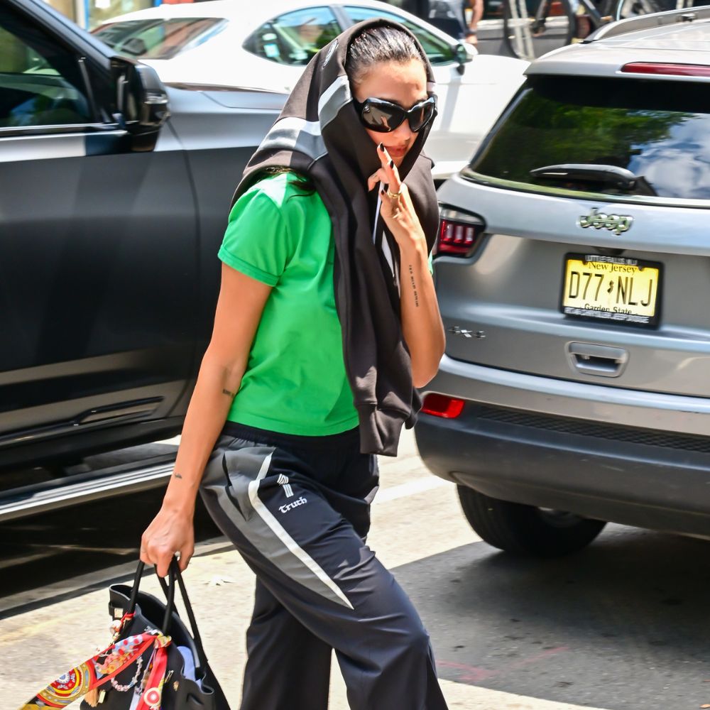 Dua Lipa wears a green t-shirt with track pants and black chunky trainers.