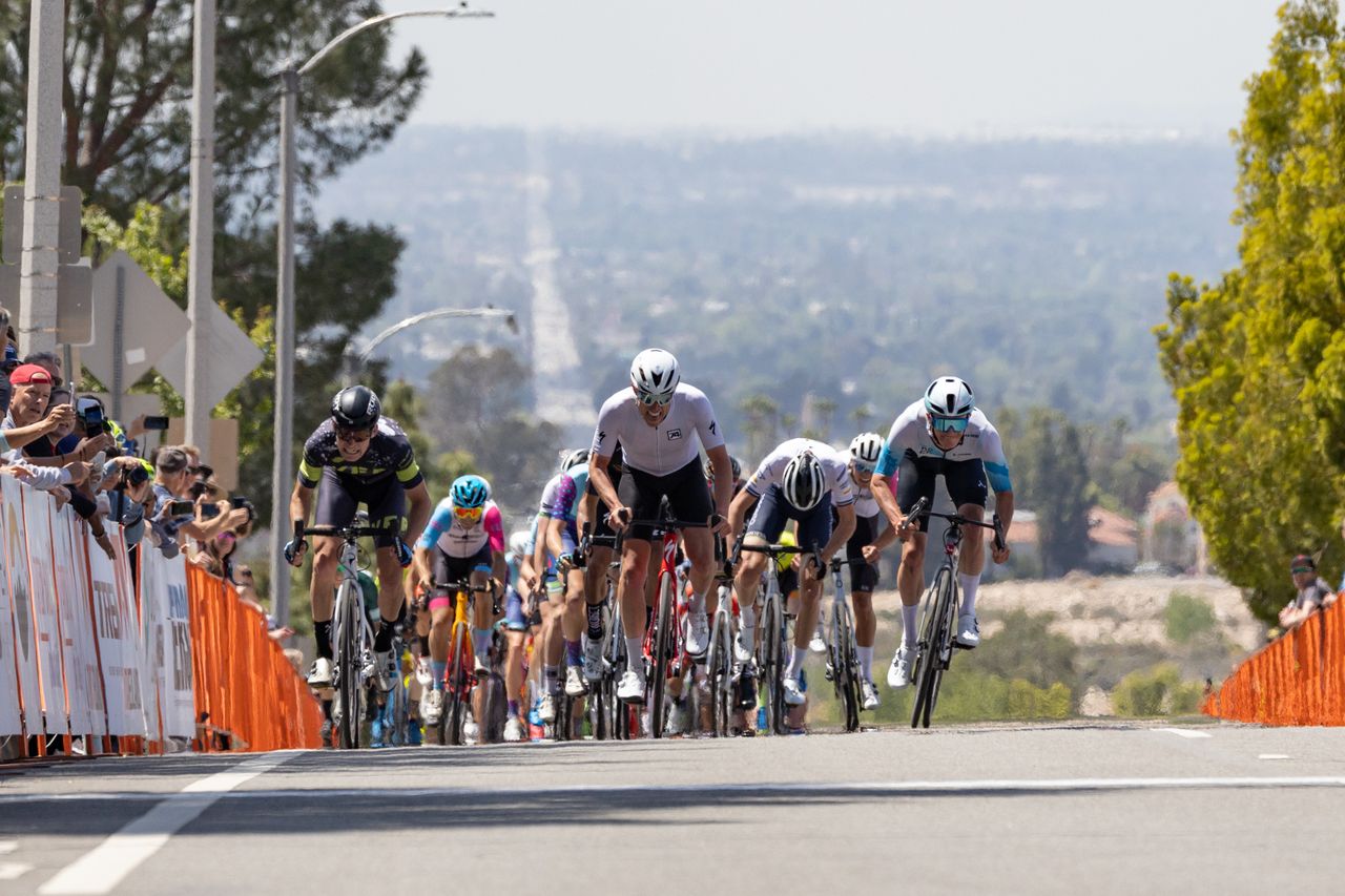 The announcers and spectators were surprised when three riders, side-by-side, appeared over the crest of the baseline climb.