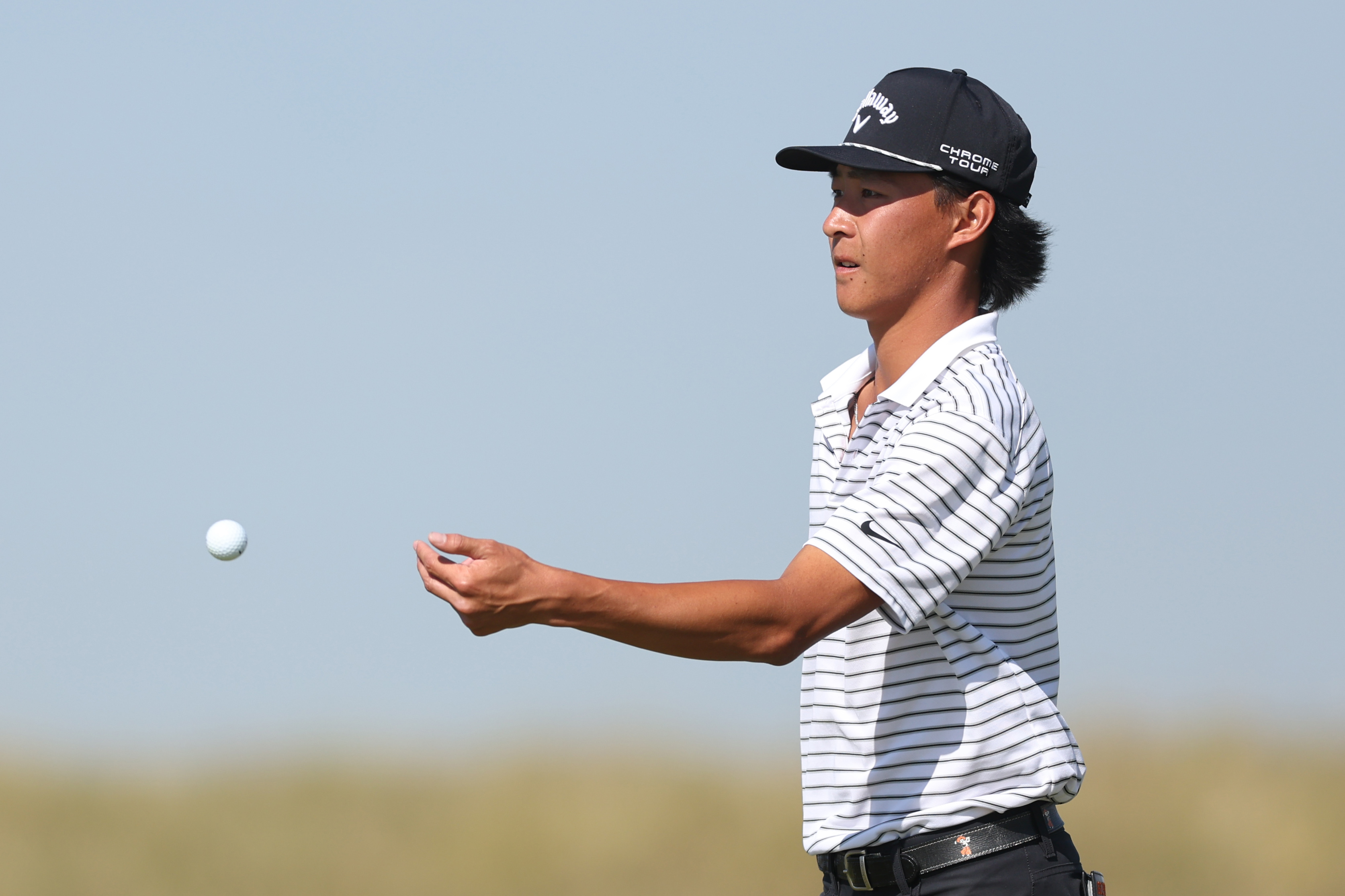 Ethan Fang throws a ball to his caddie