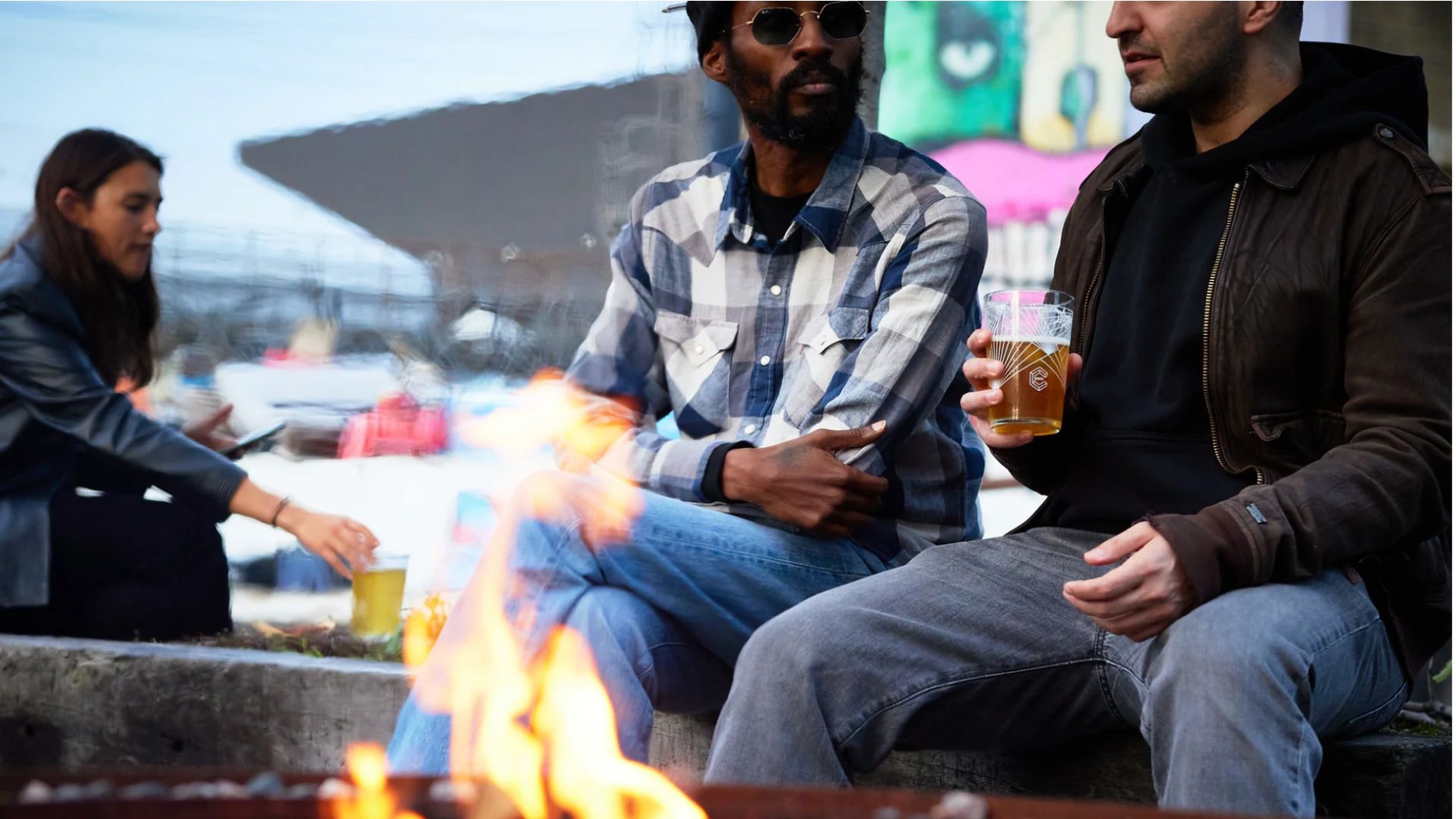 an image of two men sitting by a firepit outside Crate brewery