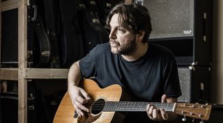 Tom Bukovac holds an acoustic guitar