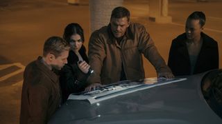 David, Karla, Jack, and Frances look at a blueprint using a flashlight in Reacher season 2