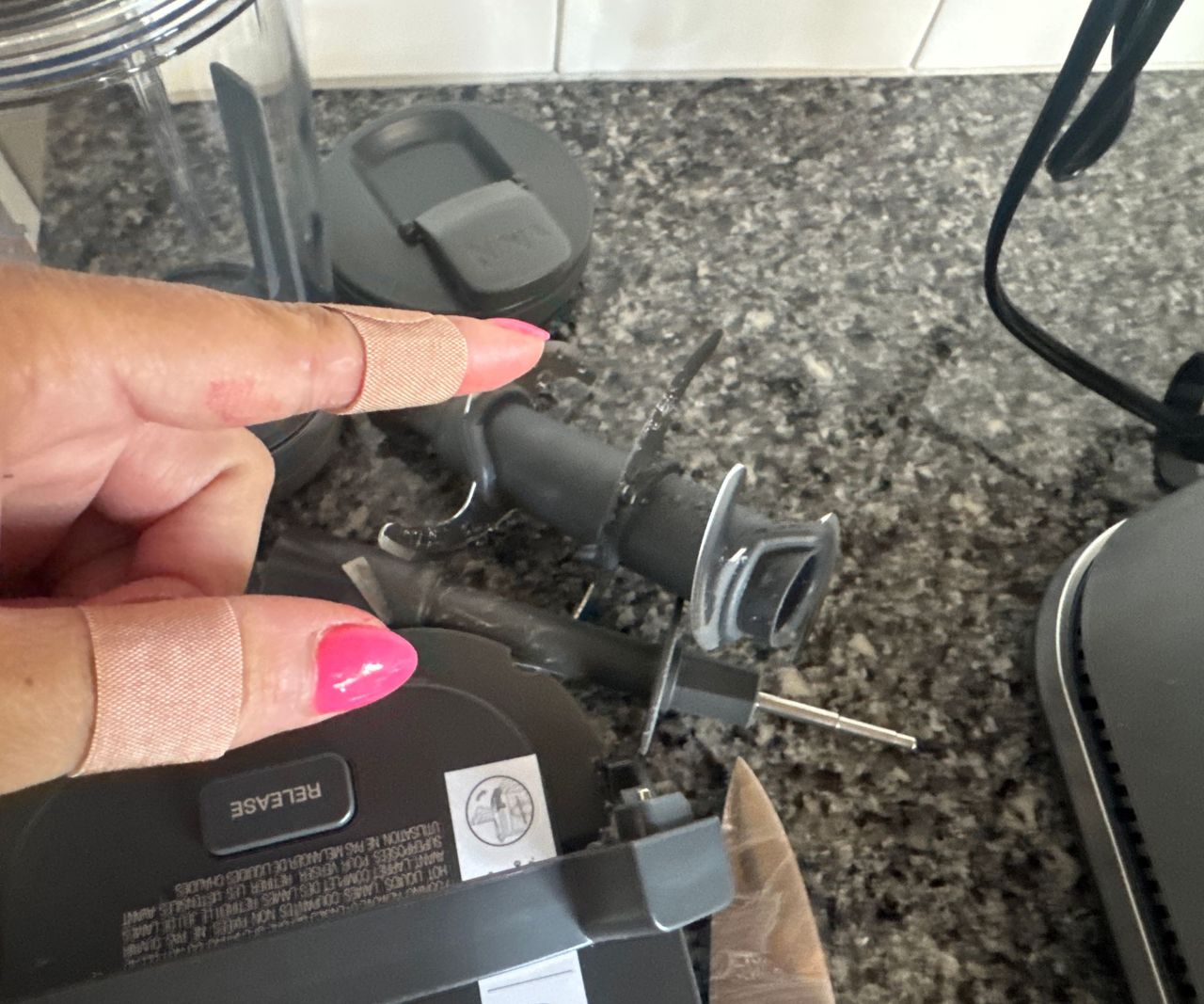 Two plasters on a thumb and forefinger, beside the Ninja Foodi Power Blender Ultimate System blades.