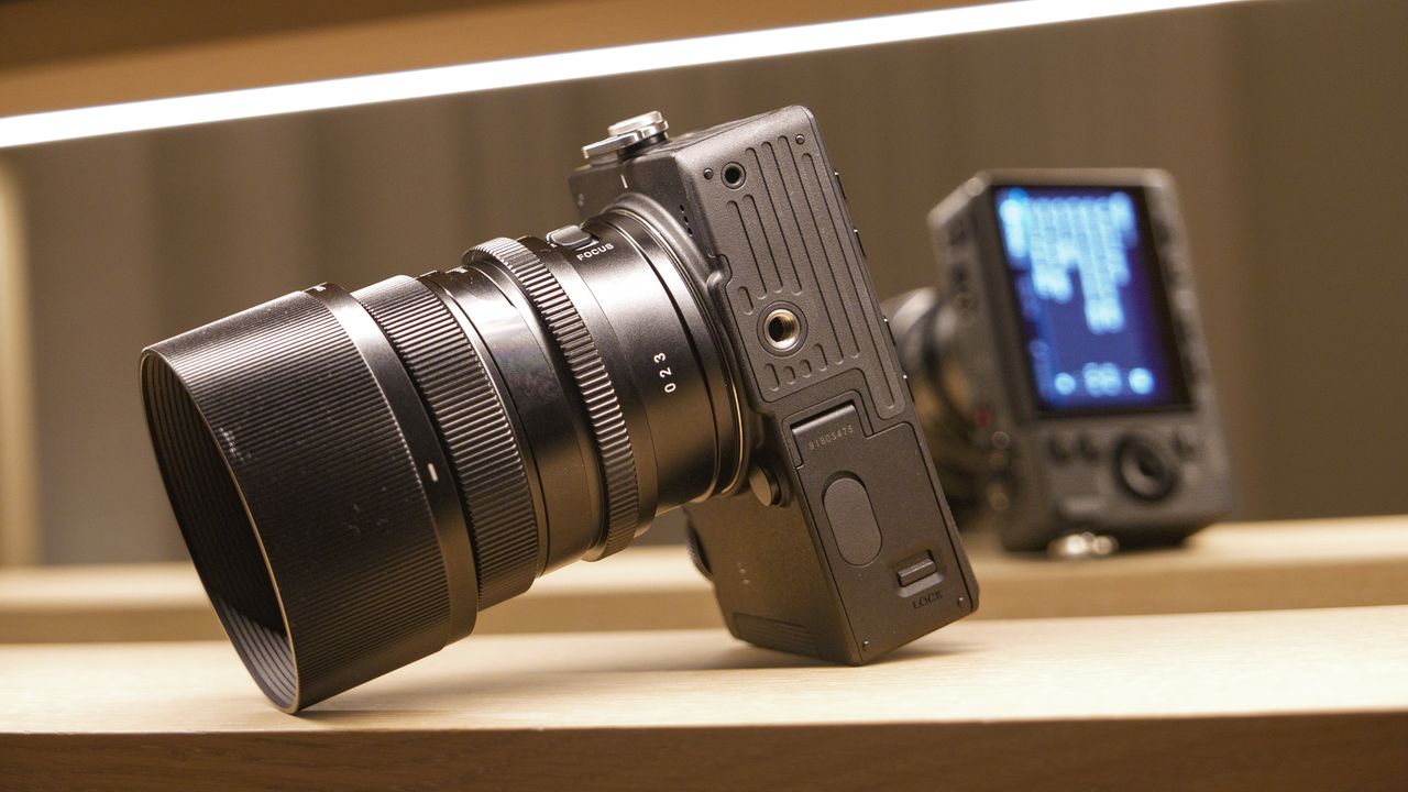 Sigma FP2 mirrorless camera with 50mm f/2 contemporary lenses attached, on a shelf, lit from above, close up of it's underside