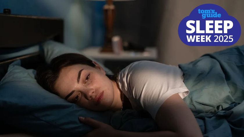 A woman lying awake in bed looking tired as a slither of sunlight lights up her face, with a Tom&#039;s Guide Sleep Week 2025 logo in the top right corner