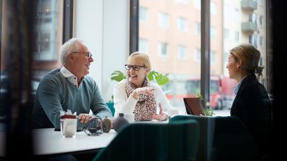 Smiling senior couple talking while sitting with Real Estate Agent in office