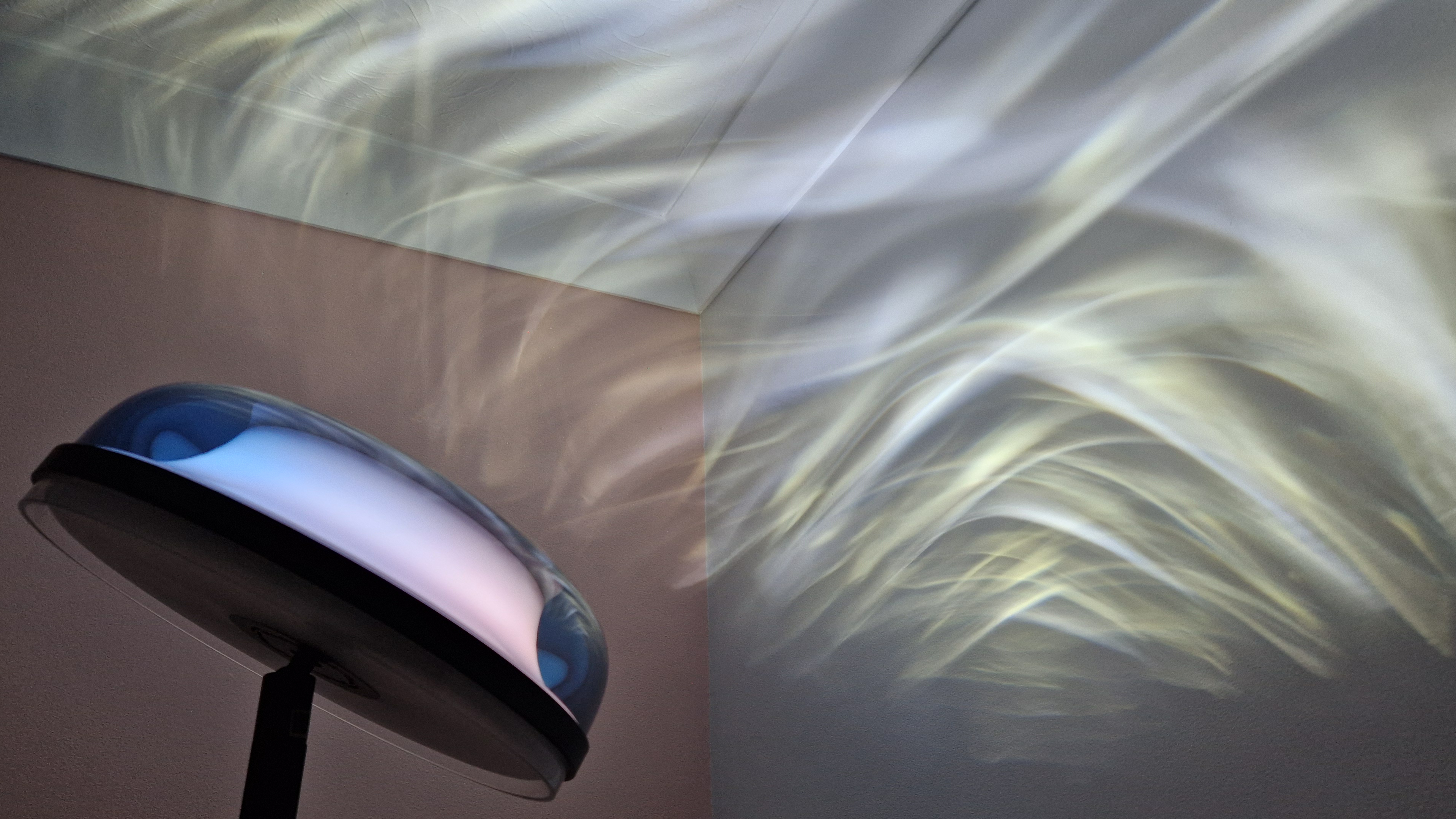 The Govee Uplighter Floor Lamp is projecting a wispy white effect onto a bedroom wall and ceiling.