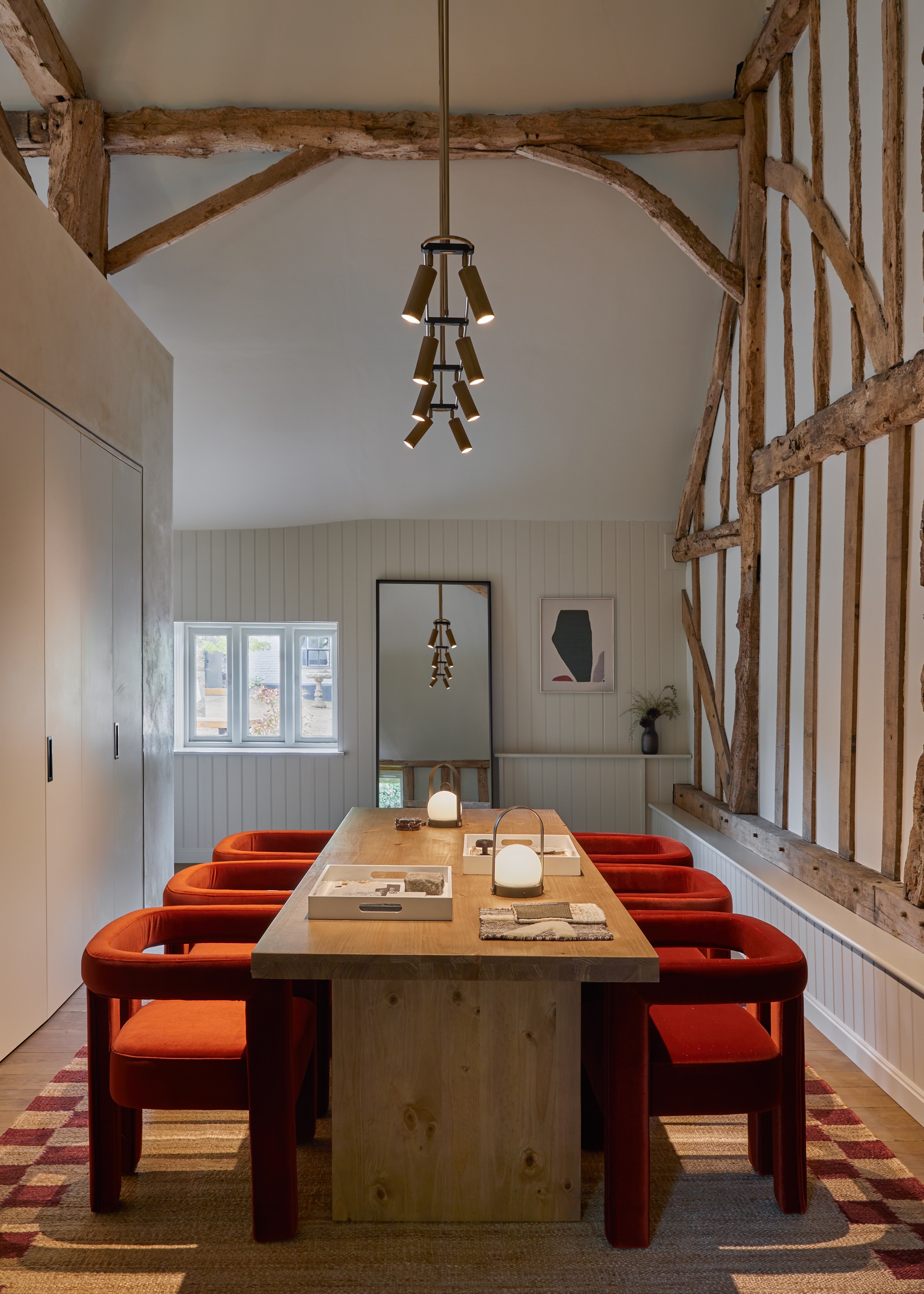 home office with rust velvet chairs, checked rug, and wall wash lighting