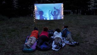 Campers watching a movie using an outdoor projector