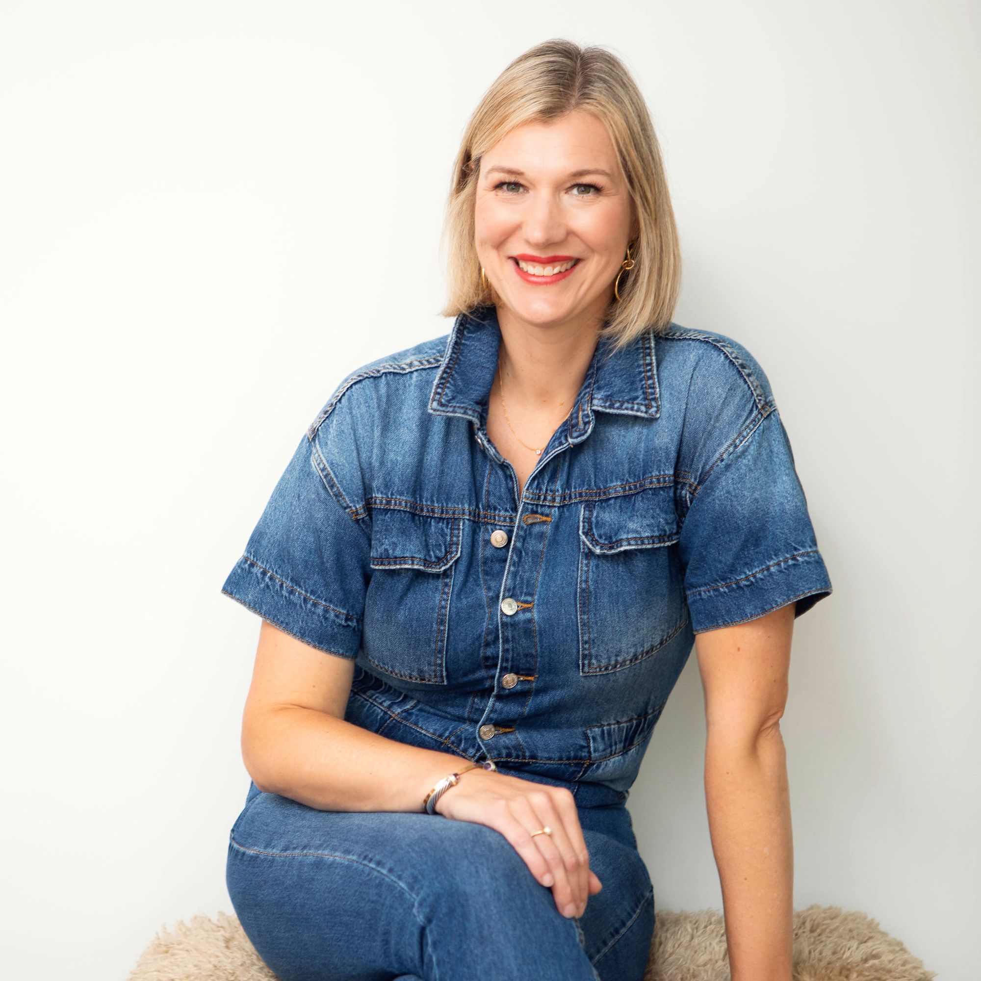 A picture of Sarah Storms, a blonde woman wearing a denim jumpsuit