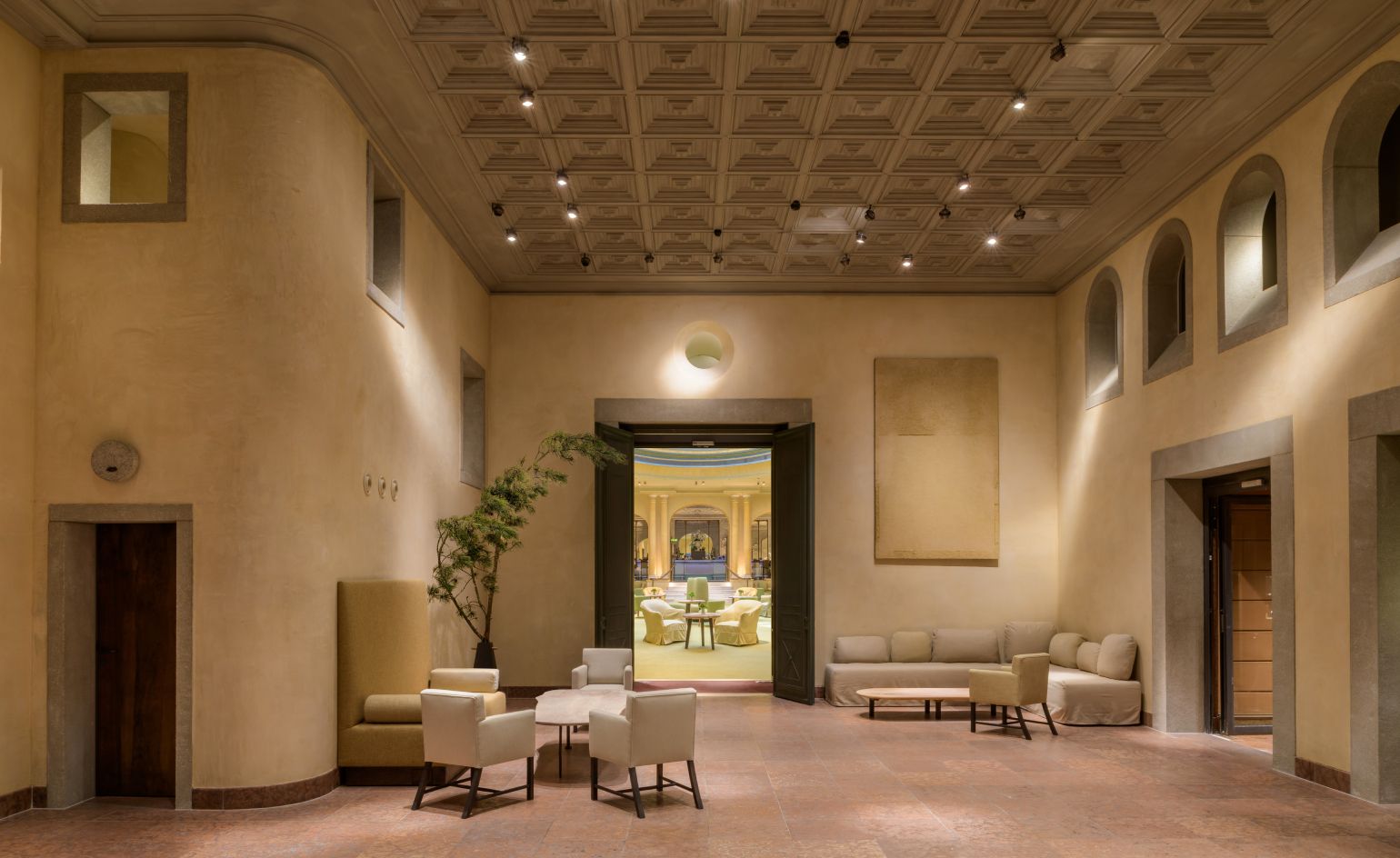 A meticulously designed hotel lobby featuring muted tones, antique furnishings, and natural materials, showcasing Axel Vervoordt's signature aesthetic.
