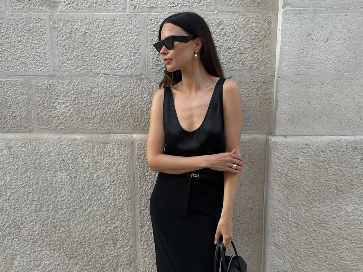 Influencer Johanna Piispa wears a maxi black skirt and a silky scoop neck blouse.