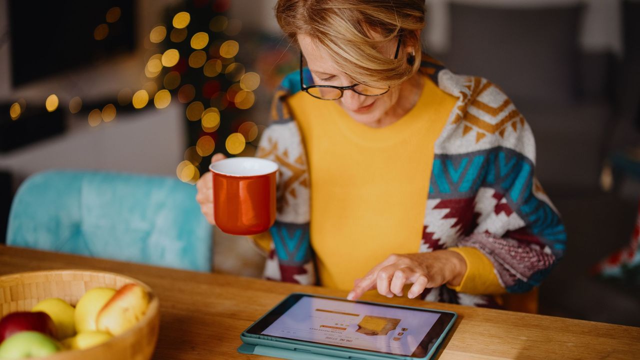 Woman enjoying online shopping and using digital tablet and credit card while sitting at dining table