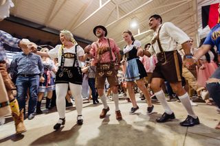 Men and women in traditional German outfits dance in Fredericksburg
