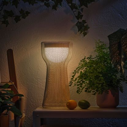 IKEA's mesh solar light place alongside plants in front of a cream wall