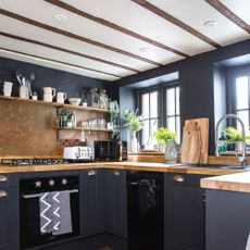Dark kitchen colour scheme with wooden worktops and appliances on display