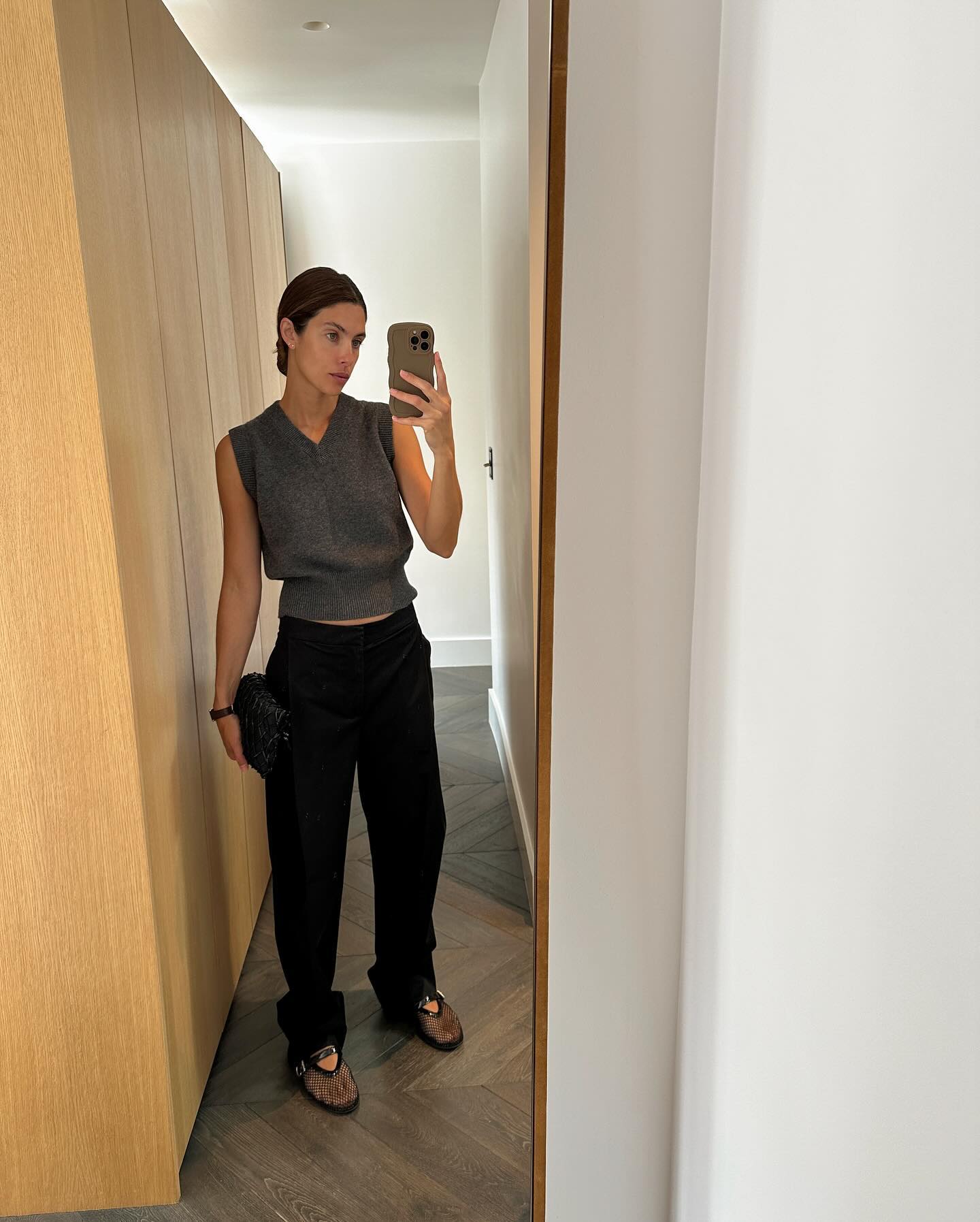 An image of @jaimeridge wearing a grey V-neck sweater vest from Paris Georgia with black tailored trousers and Alaïa's fishnet ballet galts.