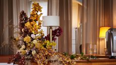 A collection of orchids displayed on a table, beside a lamp and a pair of champagne flutes