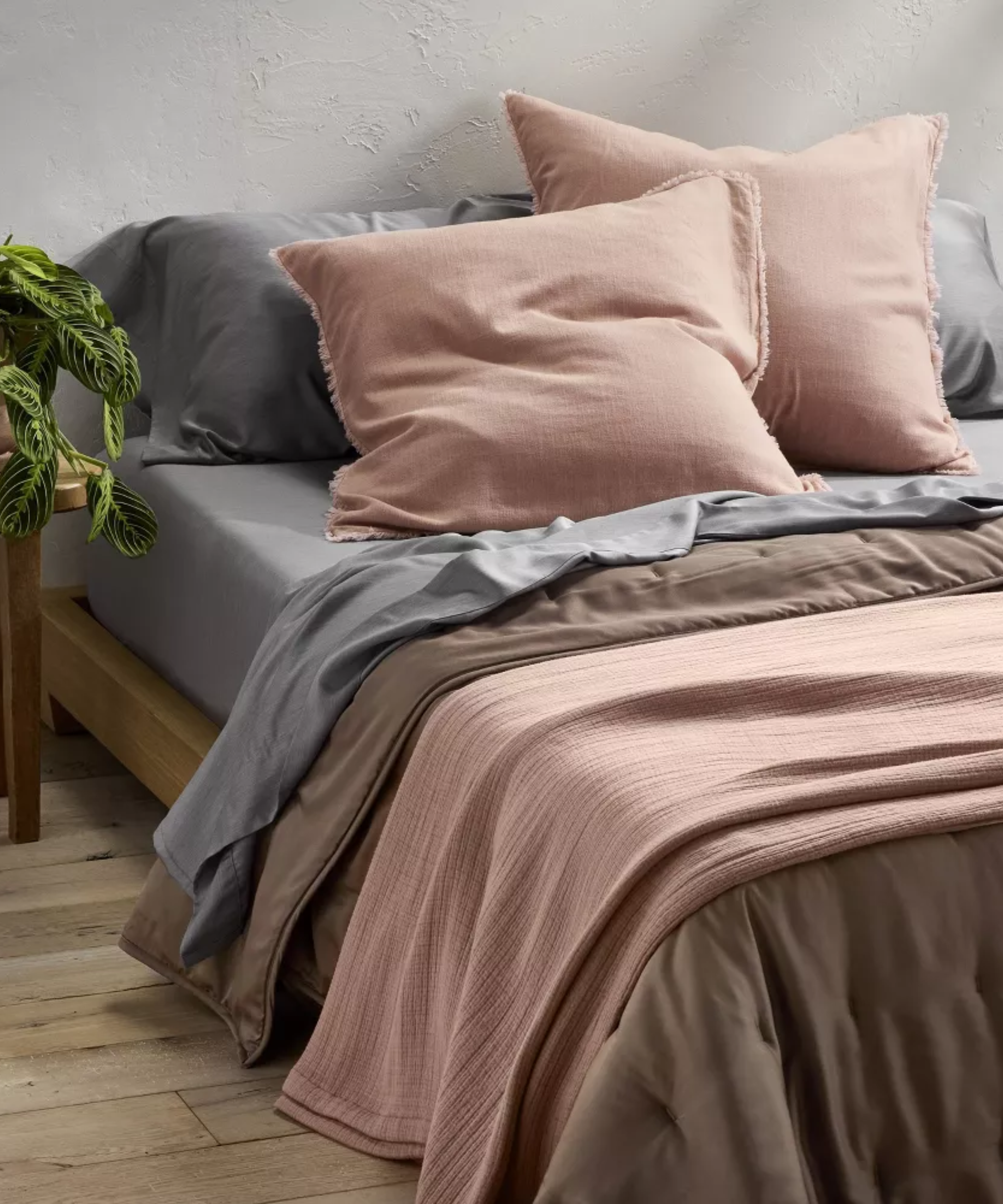 Grey, brown, and pink Casaluna bed sheets styled on a minimalist platform bed