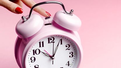 Pink alarm clock on pink background 