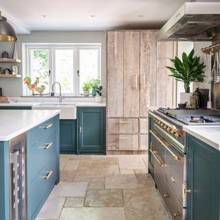 country style kitchen with stone floor tiles, reclaimed wood larder cupboard and dark blue kitchen units