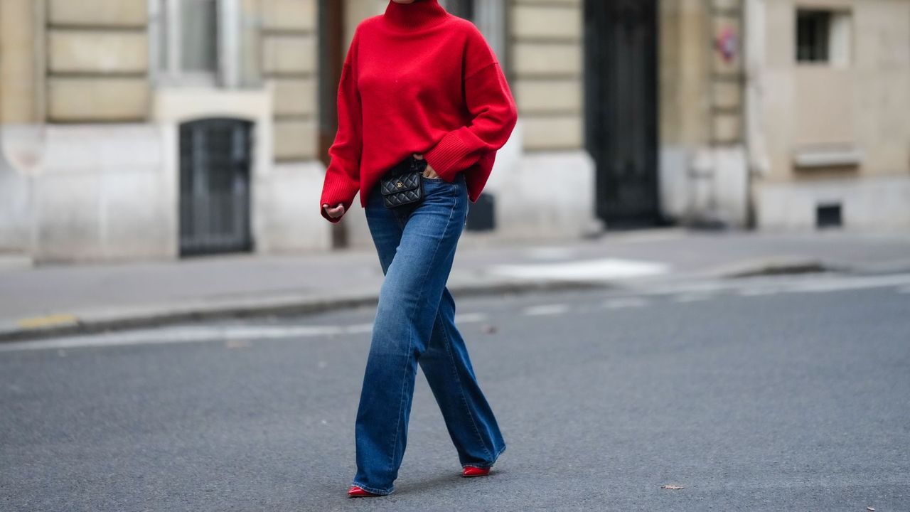 one of the 32 ways to style jeans: a woman walking in wide leg jeans a red jumper and red heels