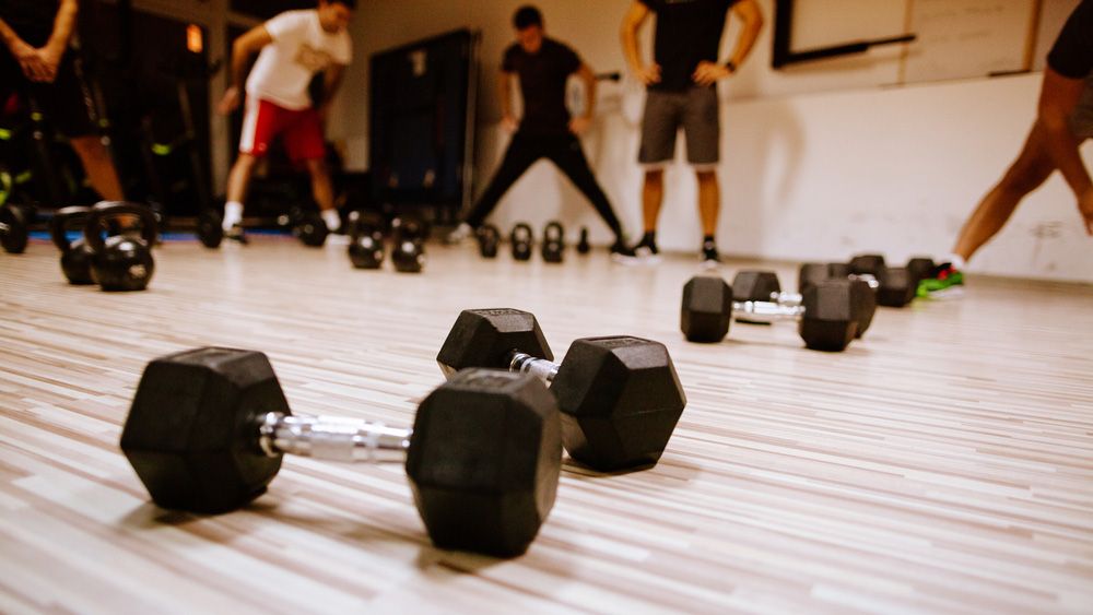 Dumbbell on floor, people stretching in background