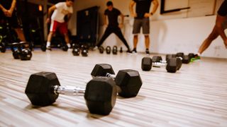 Dumbbell on floor, people stretching in background