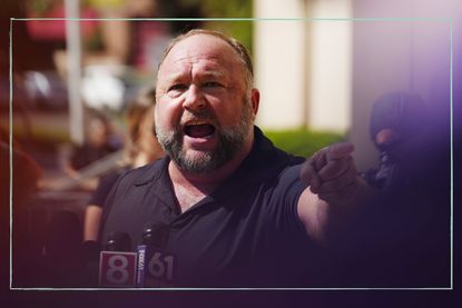 Alex Jones pictured speaking into the microphone and pointing at the crowd