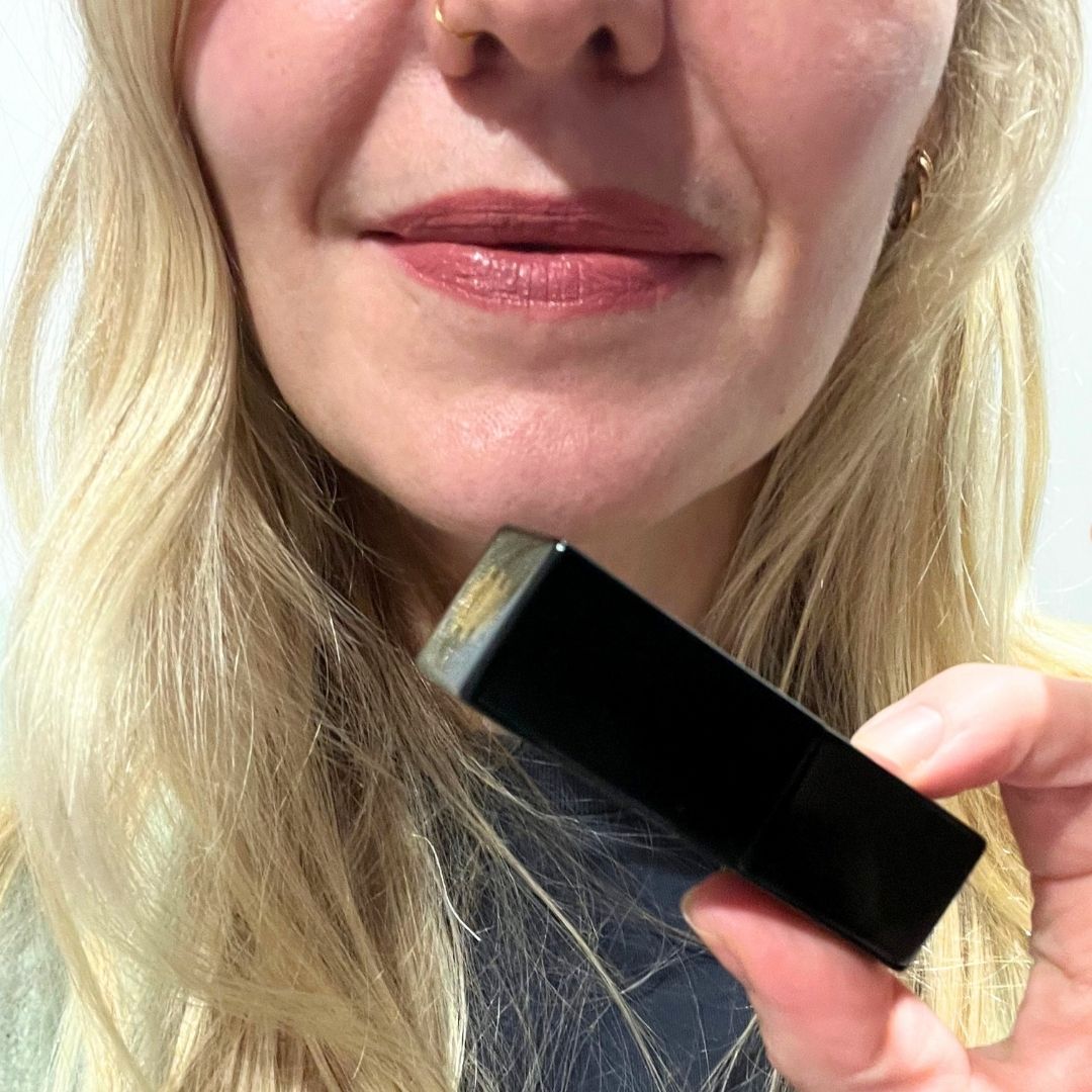 fiona mckim wearing code 8 velous lipstick in lima while holding a tube of the lipstick