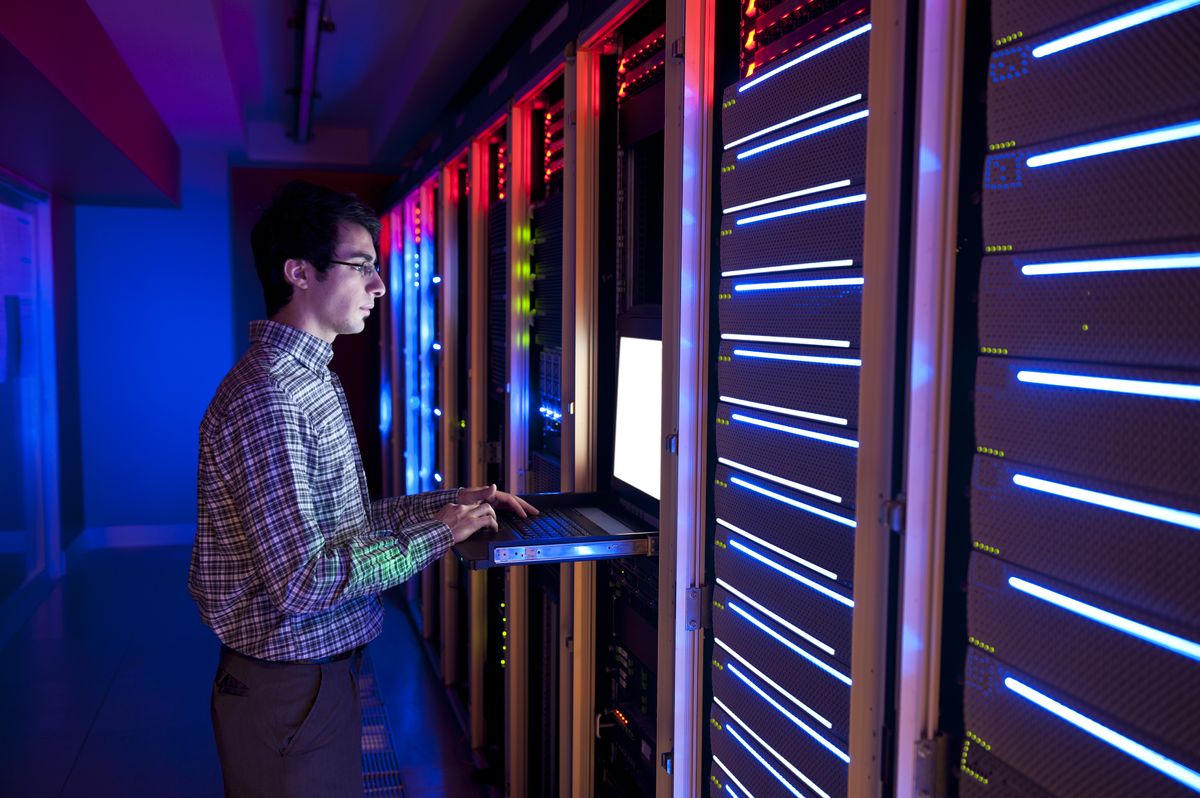 man working on laptop in server room