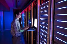 man working on laptop in server room