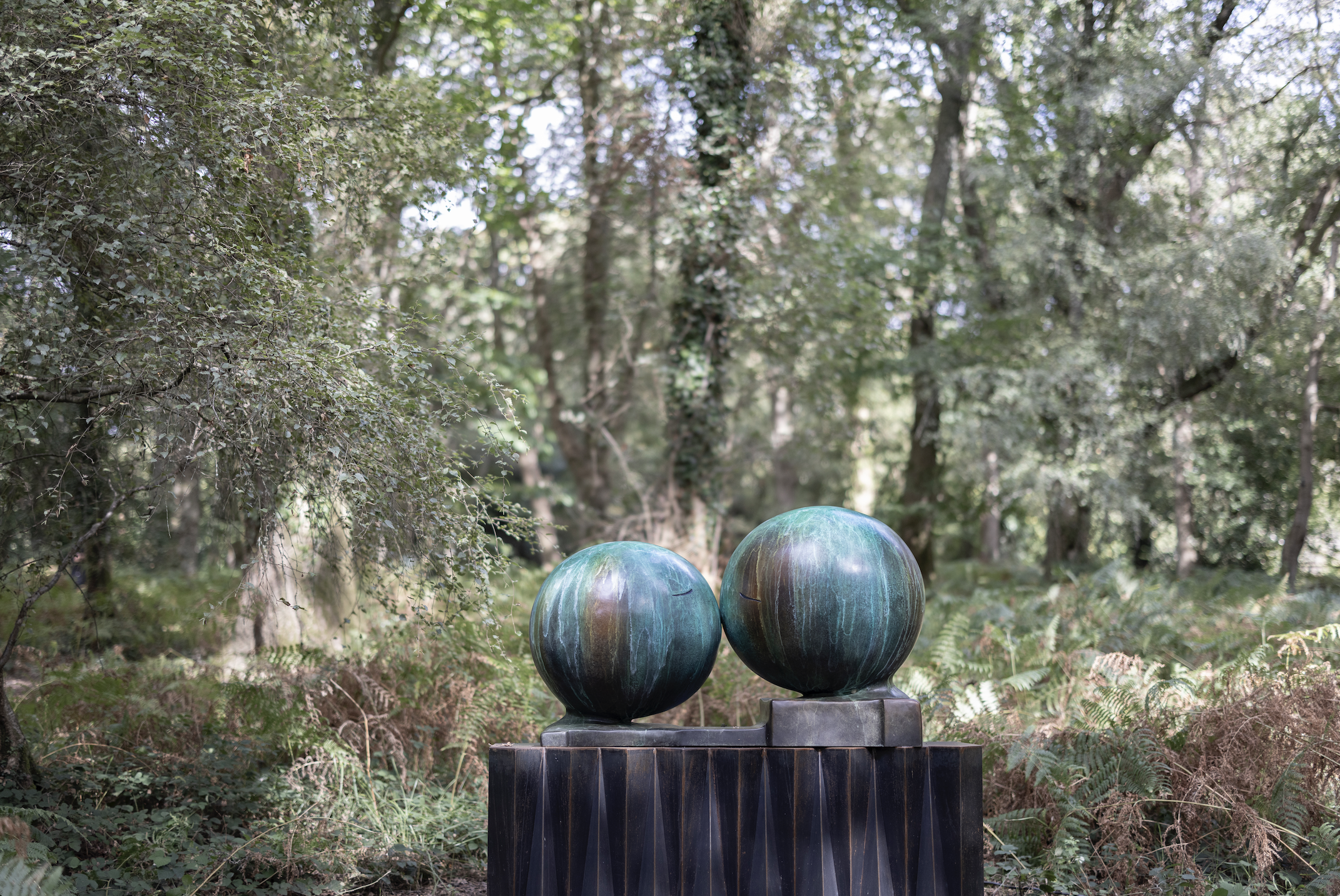 STASH, The Kiss, 2025: a sculpture of two cartoonish heads kissing in the forest
