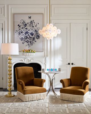 All white, luxurious living room with two burnt orange, velvet accent chairs with fringe