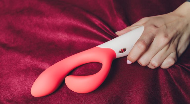 Woman in bedroom holding vibrator in hand, are vibrators bad for your health?