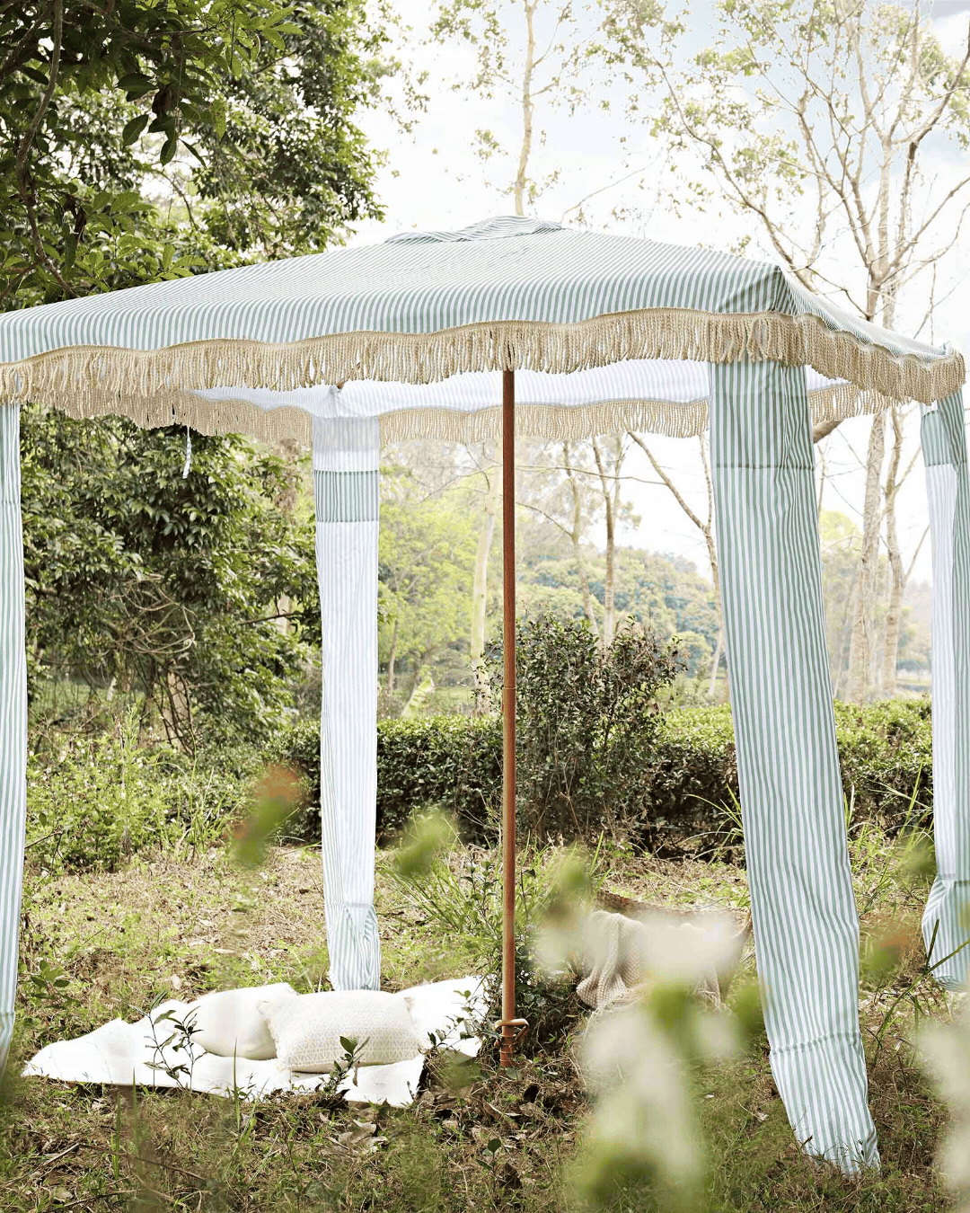 Rotating gif showcasing a stripy, white and sage cabana on a green estate.