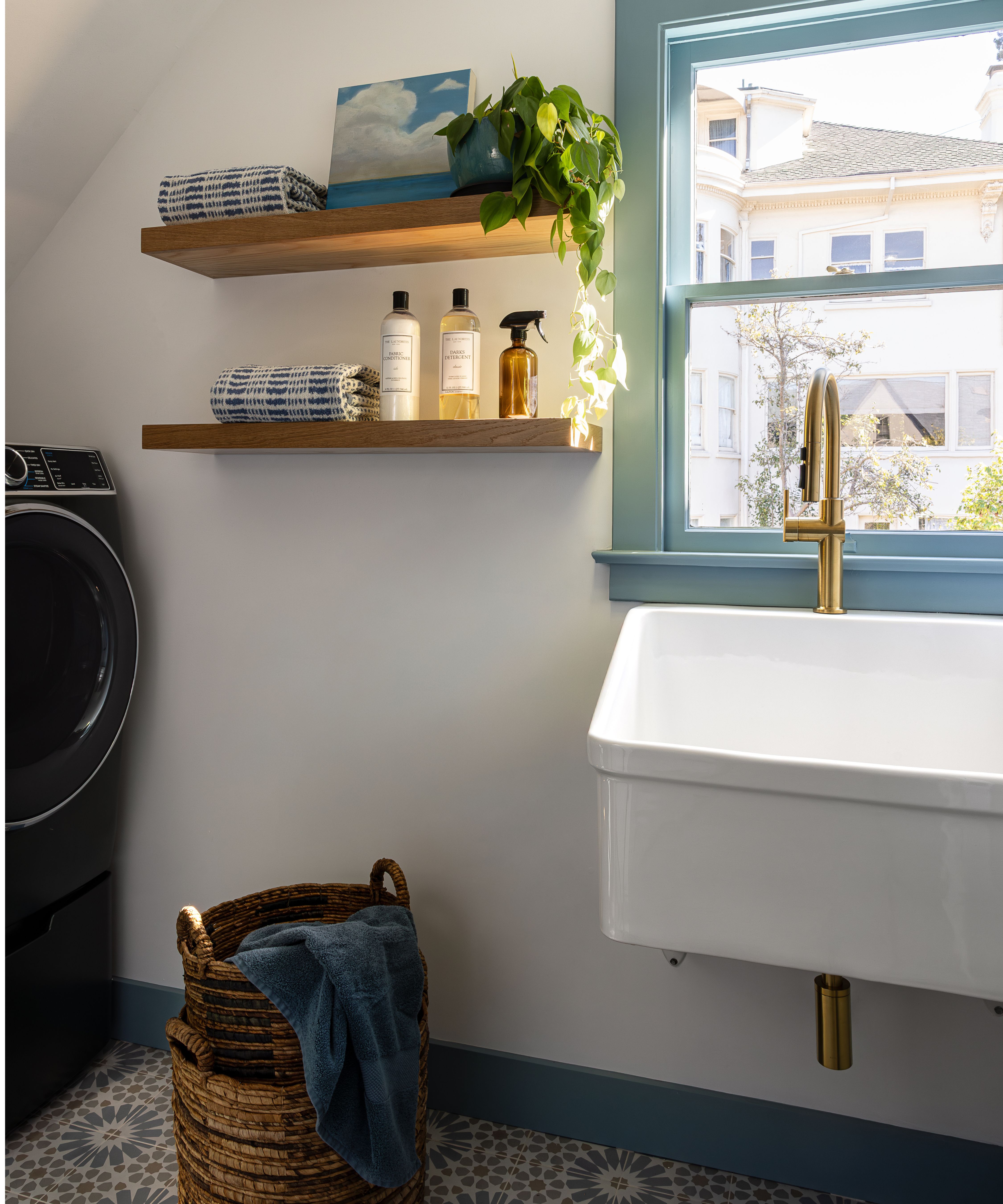 a small laundry room with blue mosaic floor tiles and blue painted wood trims