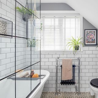 White bathroom with black towel radiator and black framed shower screen