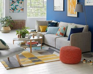 A grey modular sofa in a brightly painted living room