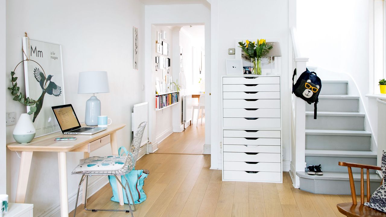 white entryway with wooden floors, desk space and grey painted stairs