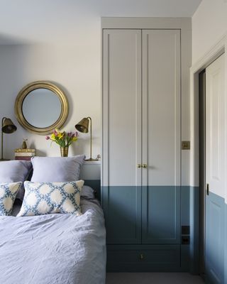 small blue and white bedroom with gold circular mirror and lighting